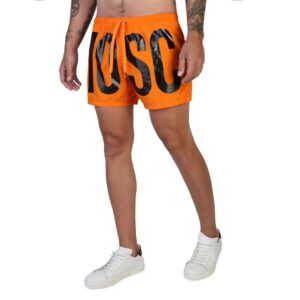 A male model wearing an orange Moschino logo print swim shorts